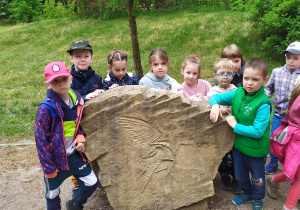 Dzieci obserwują odciśnięte w kamienach rośliny i zwierzęta